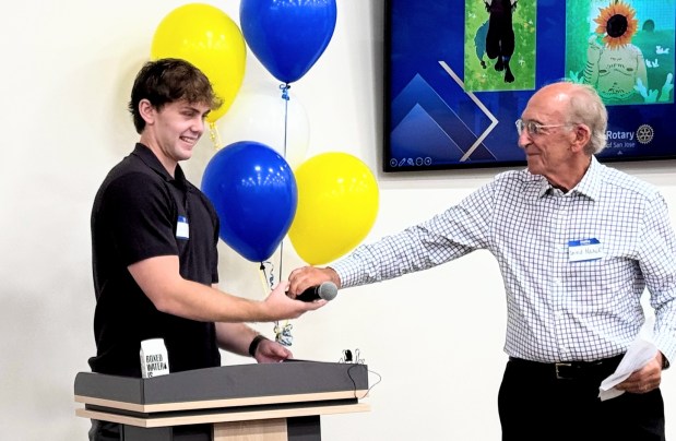 Ryan Neal accepts the microphone from his grandfather, David Neal, between speeches during the San Jose Rotary Club's Neurodivergent Artist Celebration on Sunday, May 17, 2026, at the Goodwill Opportunity Center in San Jose. (Sal Pizarro/Bay Area News Group)