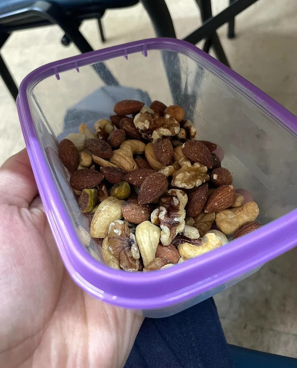 Mixed nuts including almonds, cashews, walnuts and pistachios in a clear plastic container