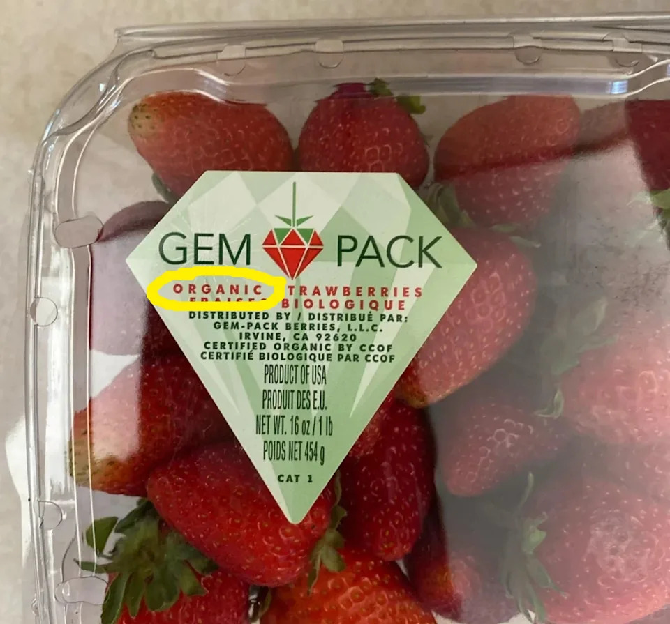 Pack of organic strawberries with label "gem pack," displayed in a plastic container