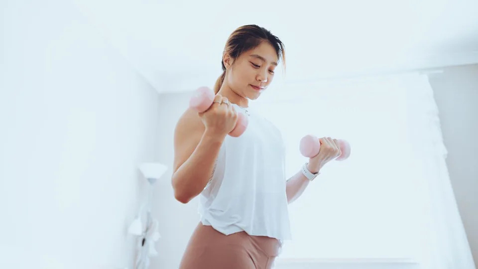 Woman exercising with dumbbells at home.