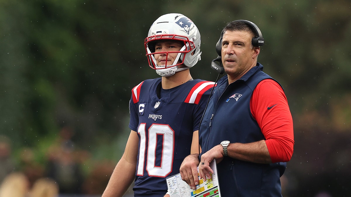 Head coach Mike Vrabel speaks with quarterback Drake Maye on the sideline at Gillette Stadium.