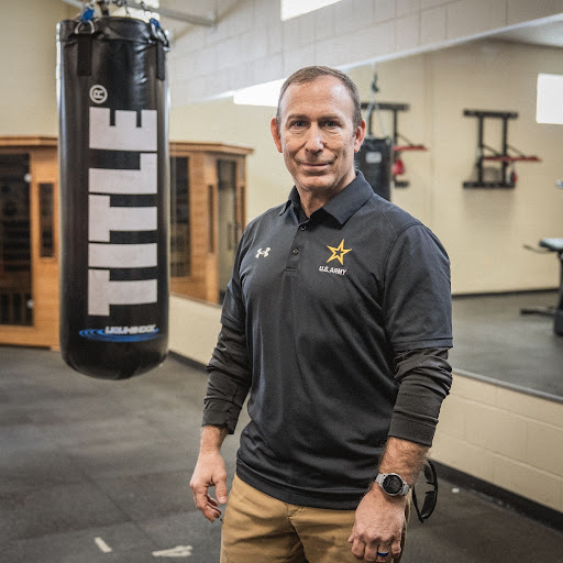 A man stands next to a hanging boxing bag.