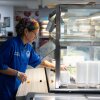 Jennifer Heylin, culinary coordinator for the Great Valley School District, cleans the salad bar in the Great Valley High School cafeteria in Malvern, Pennsylvania. She wears a blue chef's coat and a rainbow-colored bandana on her head.
